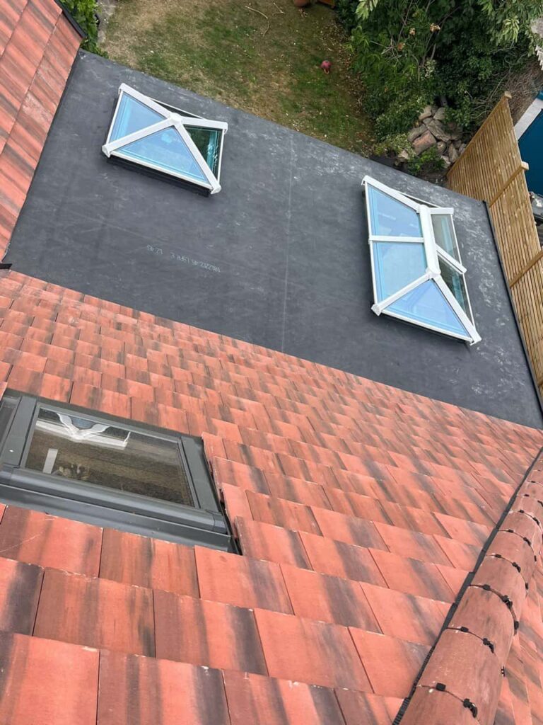 This is a photo taken from the roof ridge looking down a tiled pitched roof on to a flat roof. Works carried out by Beeston Roofing Repairs